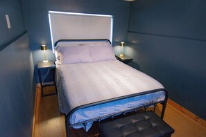 A bed with a headboard, two bedside tables with lamps, and a bench at the foot of the bed.