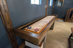 Ein Billardtisch mit Holzrahmen und Filzplatte, in einem Raum mit blauen Wänden und Holzboden.