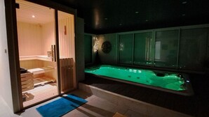 Um spa moderno com sauna de vidro, piscina aquecida verde e um banco de madeira.