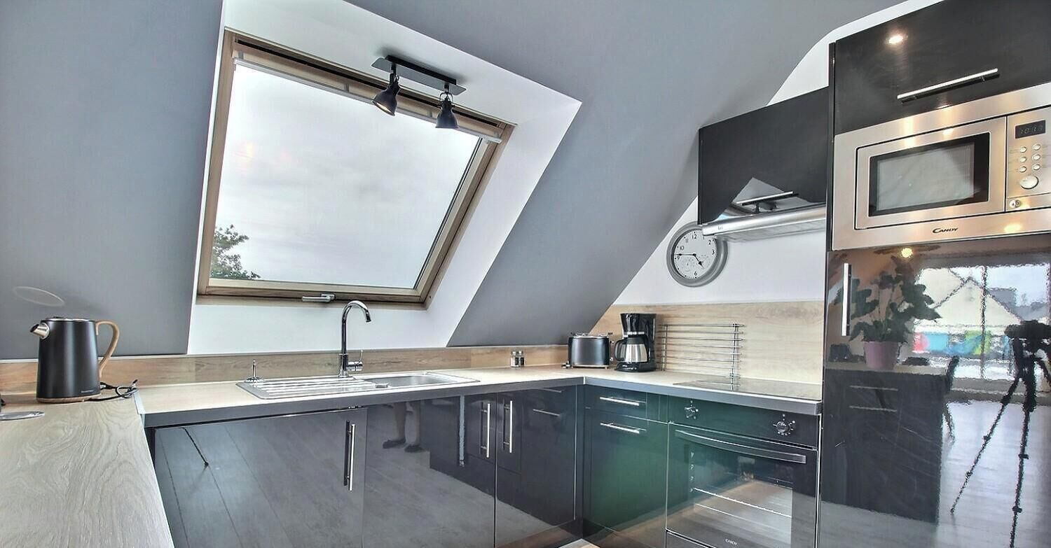 A modern kitchen with a skylight, a microwave, and a clock on the wall.