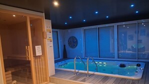 Uma área de spa com hidromassagem, piso de madeira e sauna envidraçada.