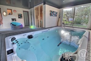 A hot tub with jets, a wooden deck, and a view of greenery outside. - The Oasis Spa - PENVENAN (PENVENAN)