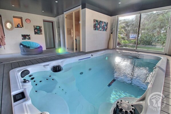 A hot tub with jets, a wooden deck, and a view of greenery outside. - The Oasis Spa - PENVENAN (PENVENAN)