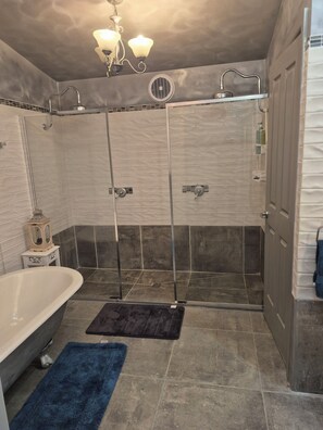 A bathroom with a bathtub, a shower enclosure, and a towel rack.