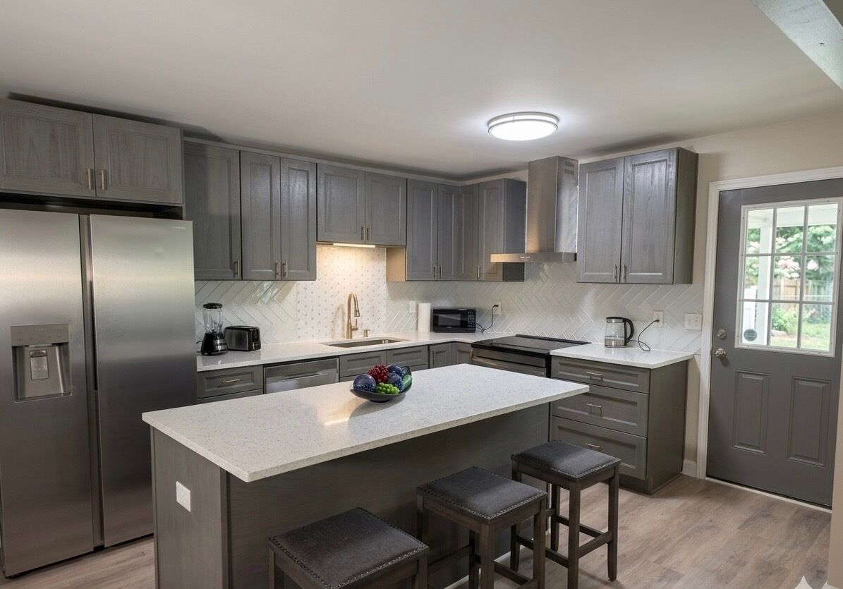 A modern kitchen with grey cabinets, stainless steel appliances, and a central island with stools.