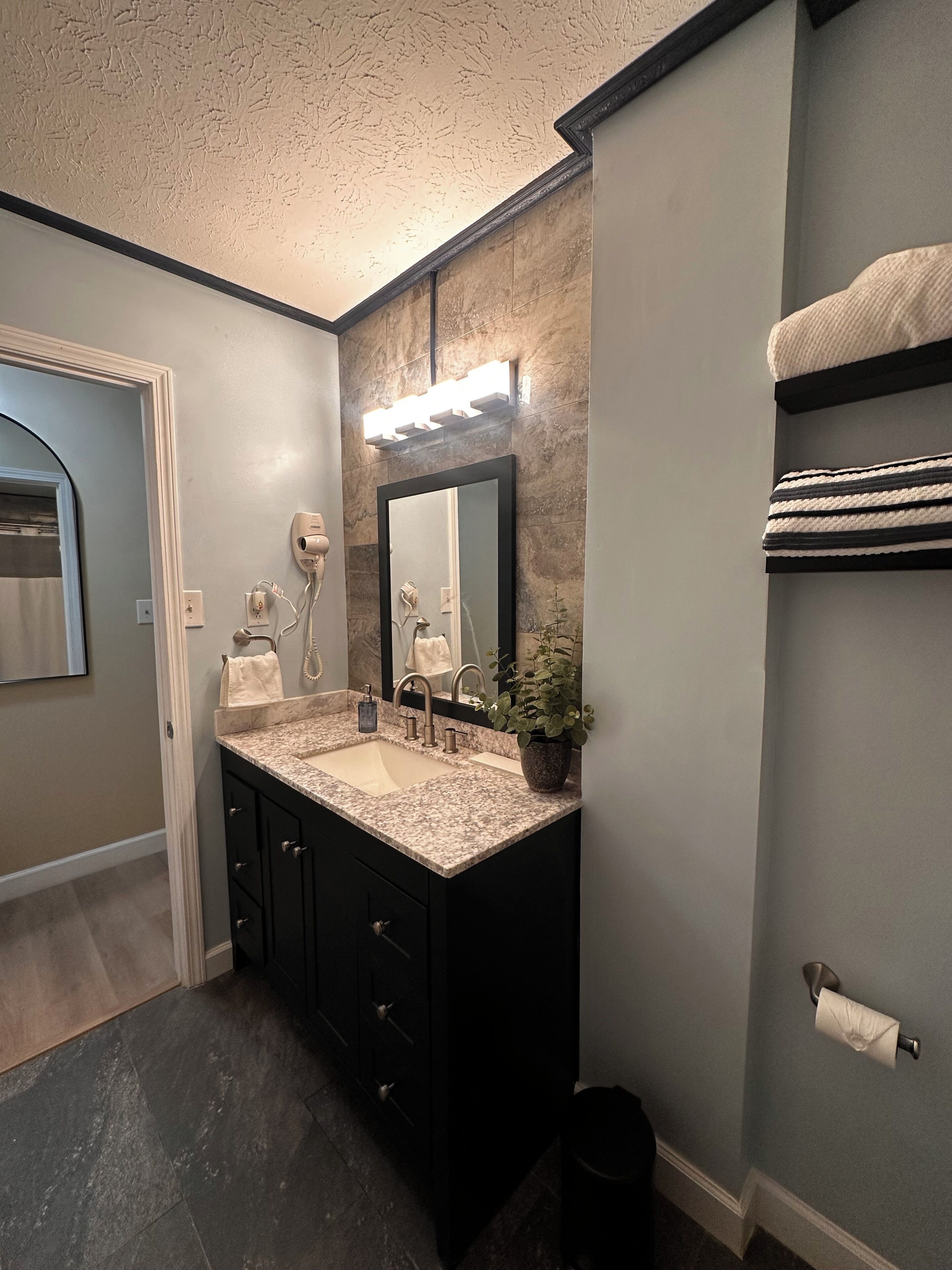 Une salle de bain avec un meuble-lavabo à deux vasques, un miroir, un porte-serviettes et une poubelle.