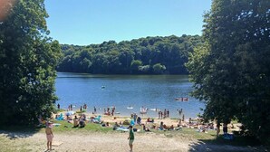 A lakeside beach with people swimming and sunbathing, surrounded by trees. - La Stabue - LANFAINS (LANFAINS)