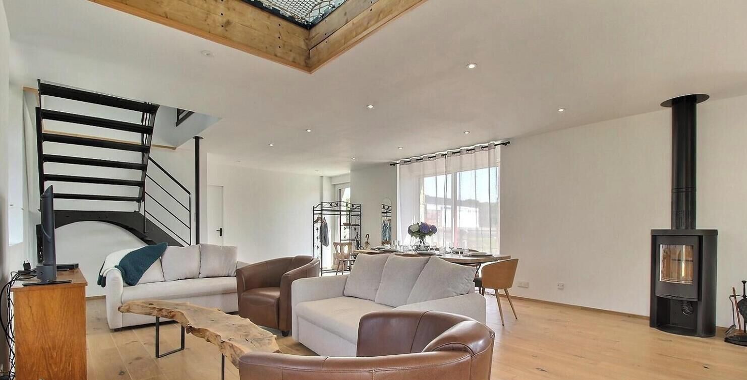 Een moderne woonkamer met een trap, een open haard en een eethoek.