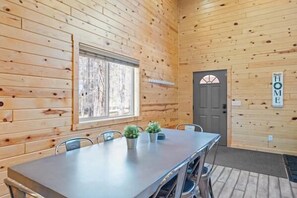 Ein Holzinterieur mit Esstisch, Stühlen, einem Fenster und einer Tür.