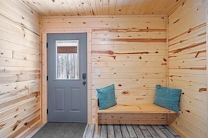A wooden cabin interior with a door, a bench with cushions, and a window. - Steelhead-Modern Yellowstone Cabin, Fiber Wi-Fi & Pine Views & Air Conditioning! (Island Park)