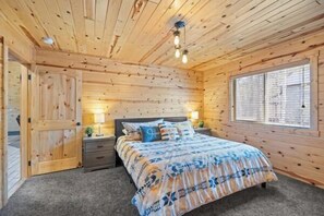 A wooden-paneled room with a bed, bedside tables, and a window. - Steelhead-Modern Yellowstone Cabin, Fiber Wi-Fi & Pine Views & Air Conditioning! (Island Park)