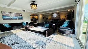 A modern living room with a sofa, coffee table, and a fireplace. - Coastal Garden: 1 Block to Stewart Beach, 4BR Sleeps 12, Luxury Bidets (Galveston)