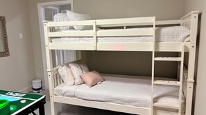 Een stapelbed met een bureau en stoel, een prullenbak en een spiegel aan de muur.