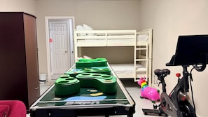 Ein Zimmer mit Stockbetten, einem Billardtisch und Fitnessgeräten.