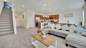 A modern living room with a grey sofa, wooden coffee table, and a staircase leading to an upper floor. - Modern 5B3B｜Near Strip｜Fiber WiFi｜TV in all Room (Las Vegas)