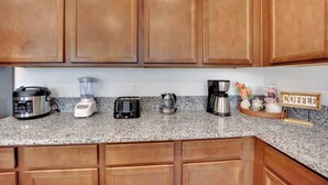 A kitchen with wooden cabinets, a granite countertop, a blender, a toaster, a coffee maker, and a coffee sign. - Modern 5B3B｜Near Strip｜Fiber WiFi｜TV in all Room (Las Vegas)