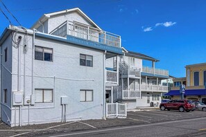 Ein mehrstöckiges Gebäude mit Balkonen, einem Parkplatz und blauem Himmel.
