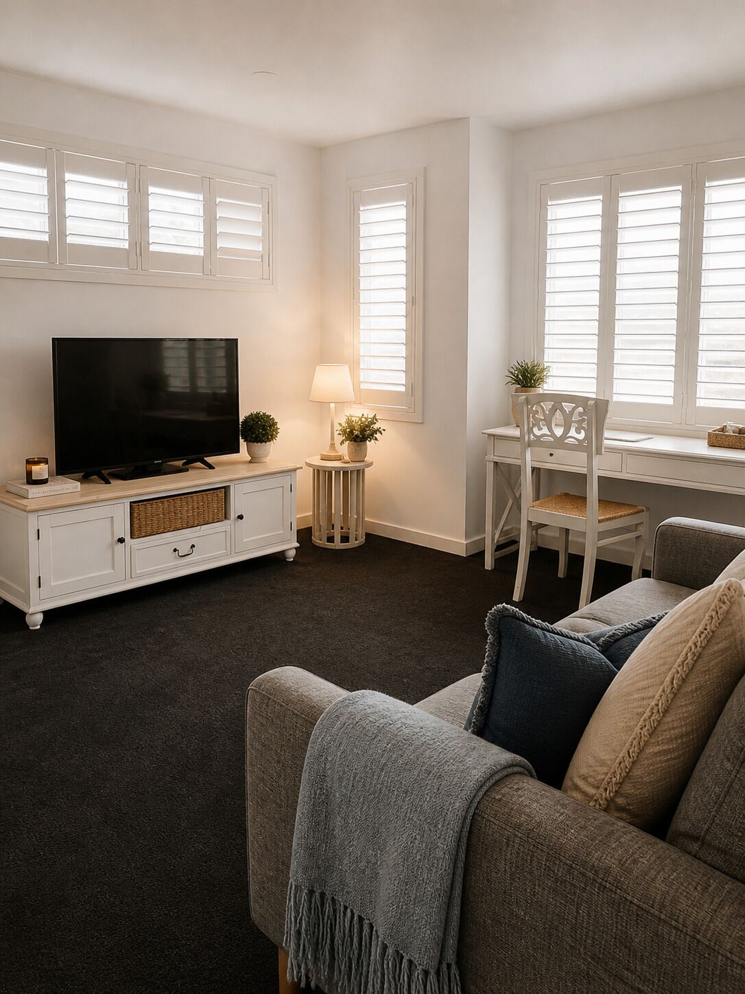 A living room with a television, a side table with a lamp, a chair, and a sofa.