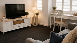En stue med fjernsyn, et sofabord med lampe, en stol og en sofa.