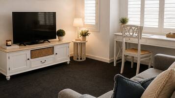 A living room with a television, a side table with a lamp, a chair, and a sofa.