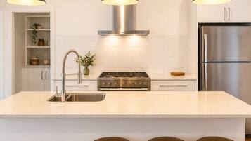 A modern kitchen with a central island, stainless steel appliances, and three pendant lights.