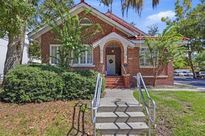 A two-story brick building with a front entrance, a small porch, and a mailbox.