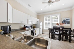 A modern kitchen with white cabinets, a built-in oven, a microwave, and a coffee maker.