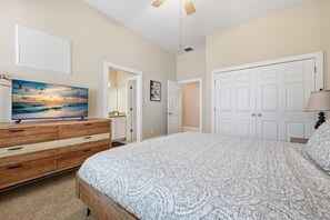 A bedroom with a bed, dresser, television, and wardrobe.