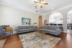 A living room with a grey sofa, a coffee table, and a ceiling fan.