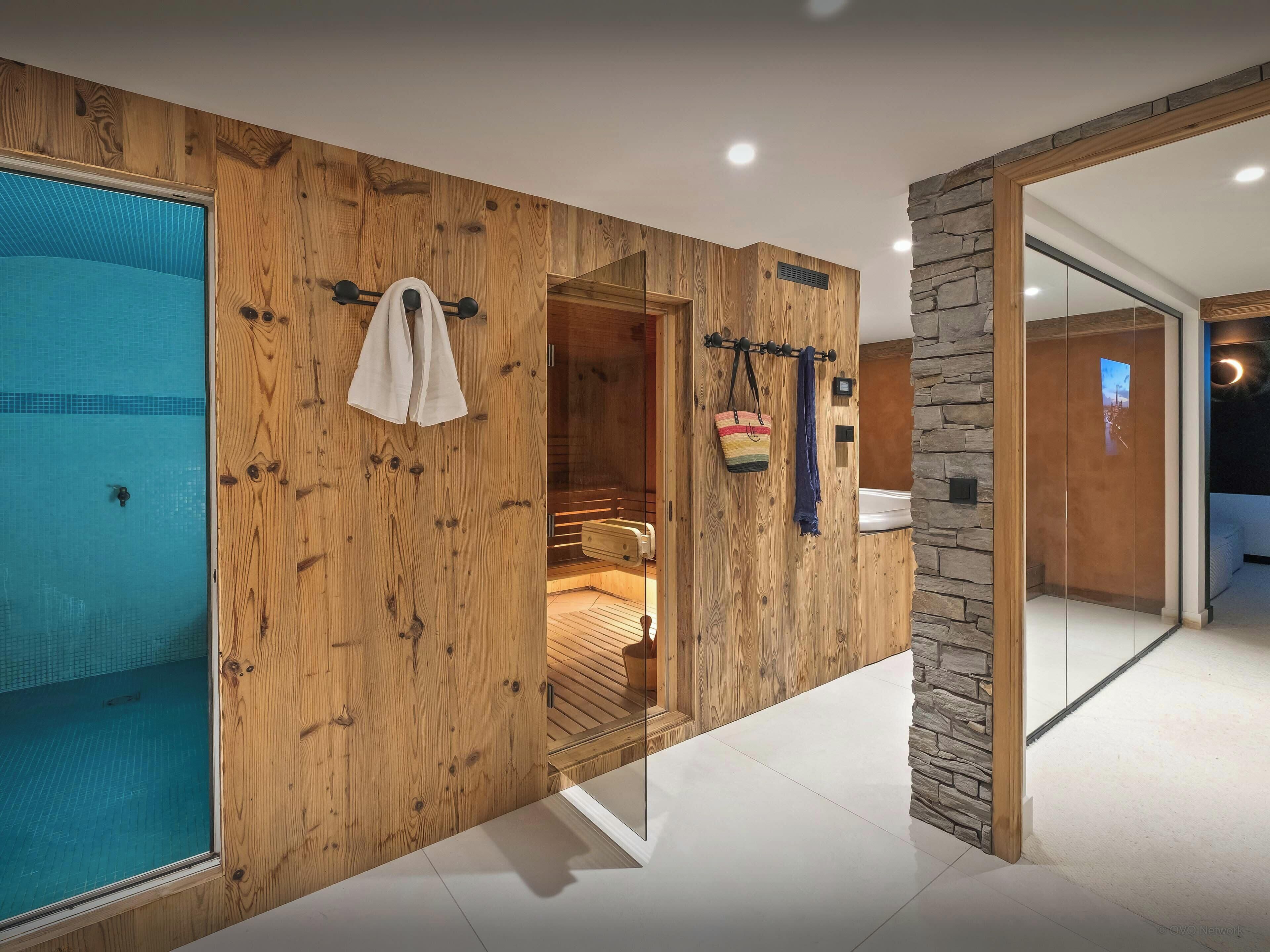 A wooden wall with a towel rack, a glass door leading to a pool, and a stone wall.