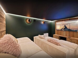 A modern room with a dark green wall, a mounted television, and a cozy seating area with a fluffy pillow.