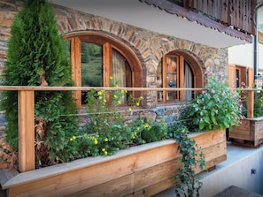 A stone building with wooden windows and a wooden deck.
