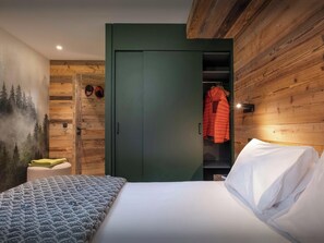 A bedroom with a bed, a green wardrobe, and a coat hanging inside.