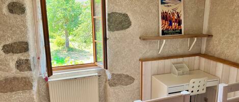 Une pièce avec une fenêtre, un radiateur, un lit, un bureau et une affiche accrochée au mur.
