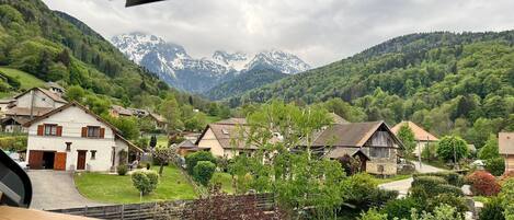 A view from a window overlooking a village with traditional houses and a mountain range in the background.