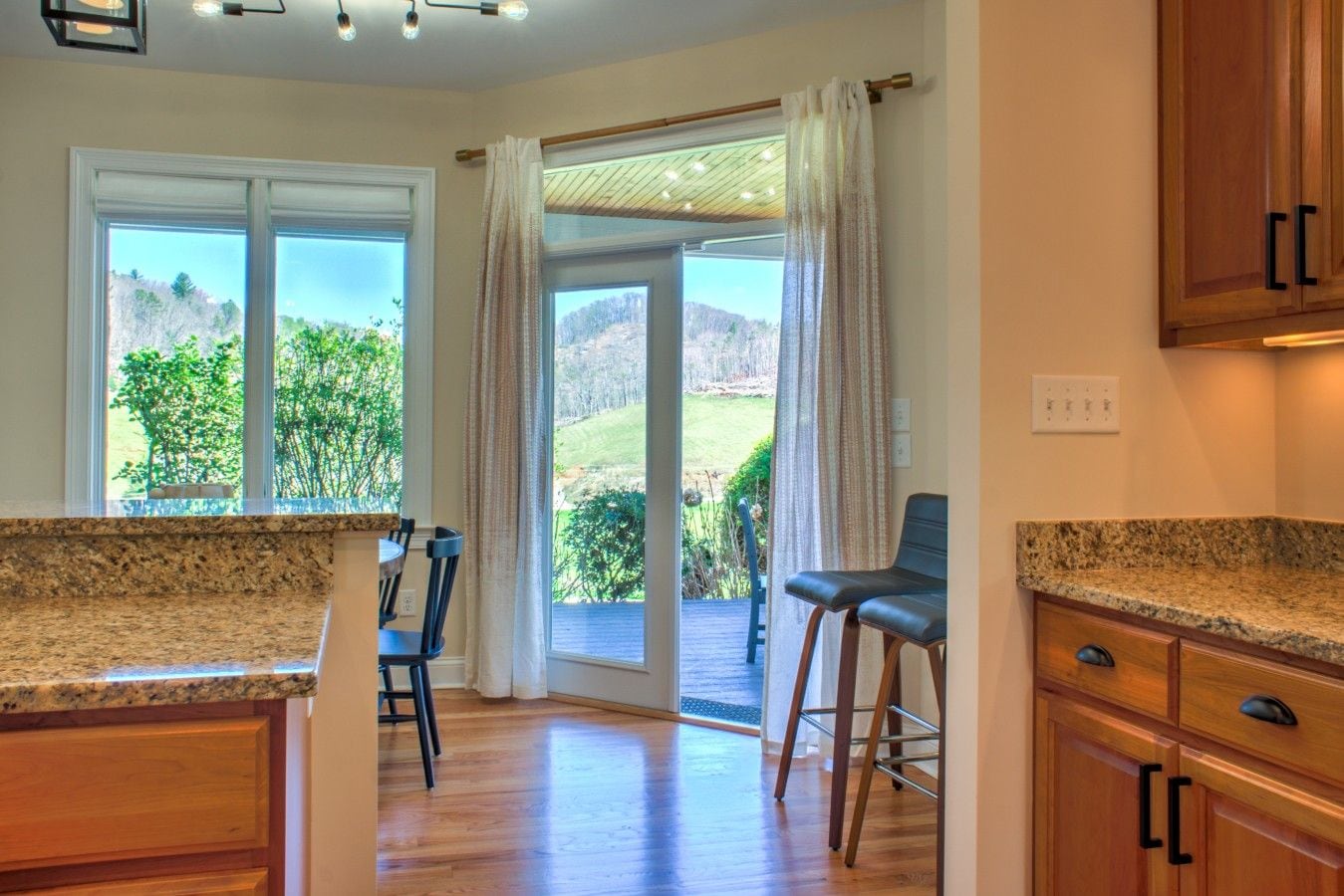 A kitchen with granite countertops, wooden cabinets, and a view of a landscaped outdoor area through large sliding glass doors.