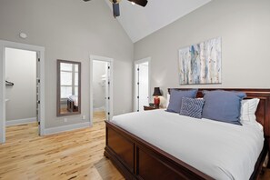 A bedroom with a large bed, wooden flooring, a ceiling fan, and a painting on the wall. - McLemore Resort - 78 Canyon Ridge Road - Mountain Home Near Resort Entrance (Rising Fawn)