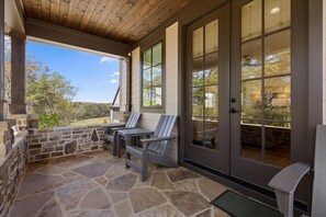 Eine überdachte Terrasse mit Steinboden, zwei Adirondack-Stühlen und einer Steinwand.