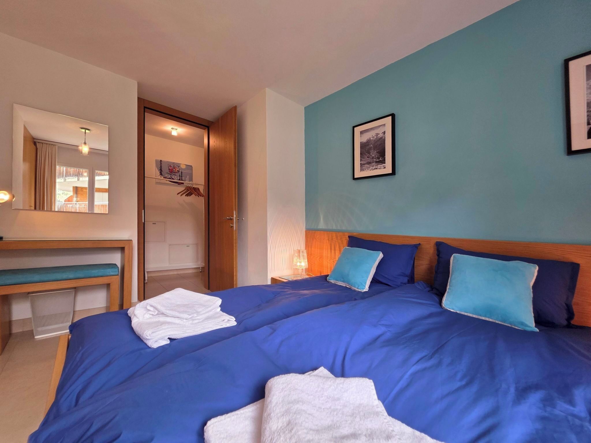 A hotel room with a bed, a bench, a mirror, and a door leading to a balcony.