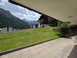 A hotel with a terrace overlooking a mountainous landscape.