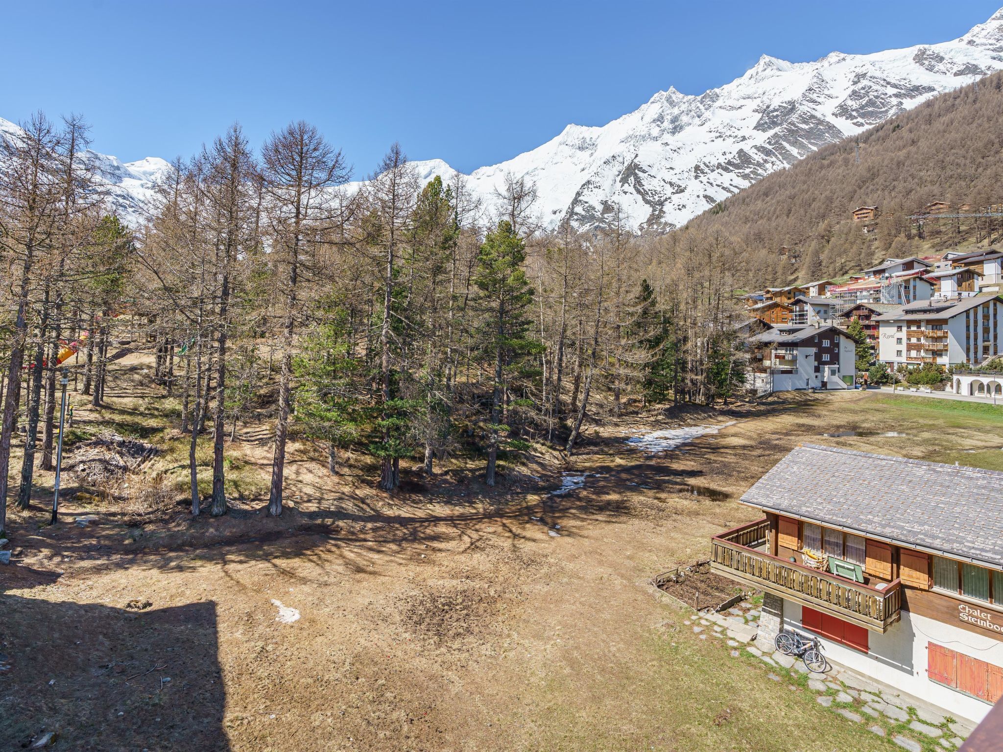 A mountain lodge with a chalet-style building, surrounded by trees and snow-capped mountains.