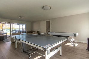 A ping pong table in a room with a view of a deck and outdoor area. - The Blue Bay House on Lake Mille Lacs. Waterfront! Near Trails! Walk to town! (Isle)