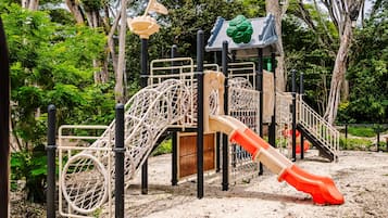 Un parque infantil con tobogán, estructuras para escalar y una casita de madera.
