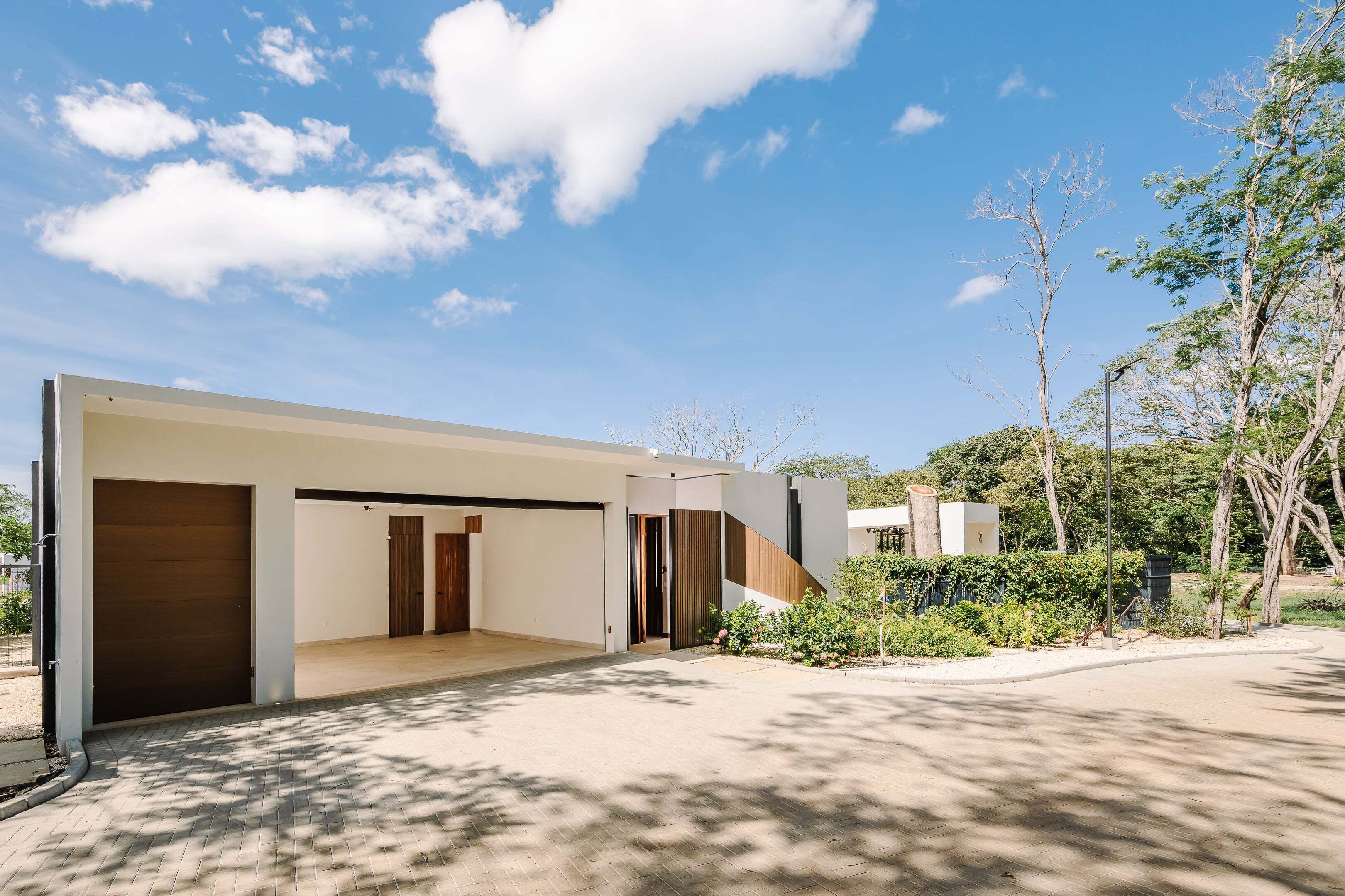 A modern building with a flat roof, large windows, and a paved driveway.