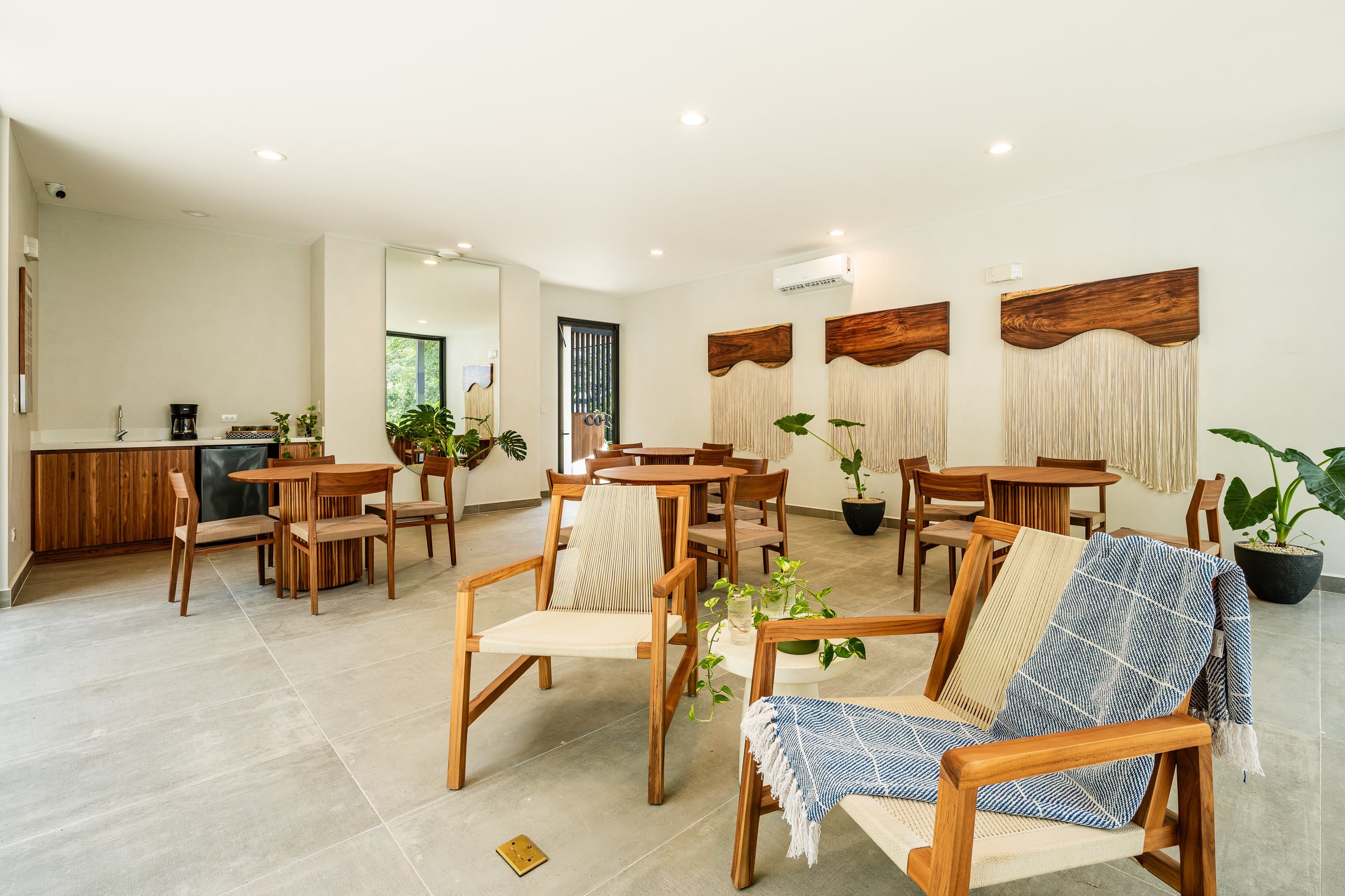A spacious living area with wooden furniture, a coffee machine, and a dining area with a view of greenery outside.