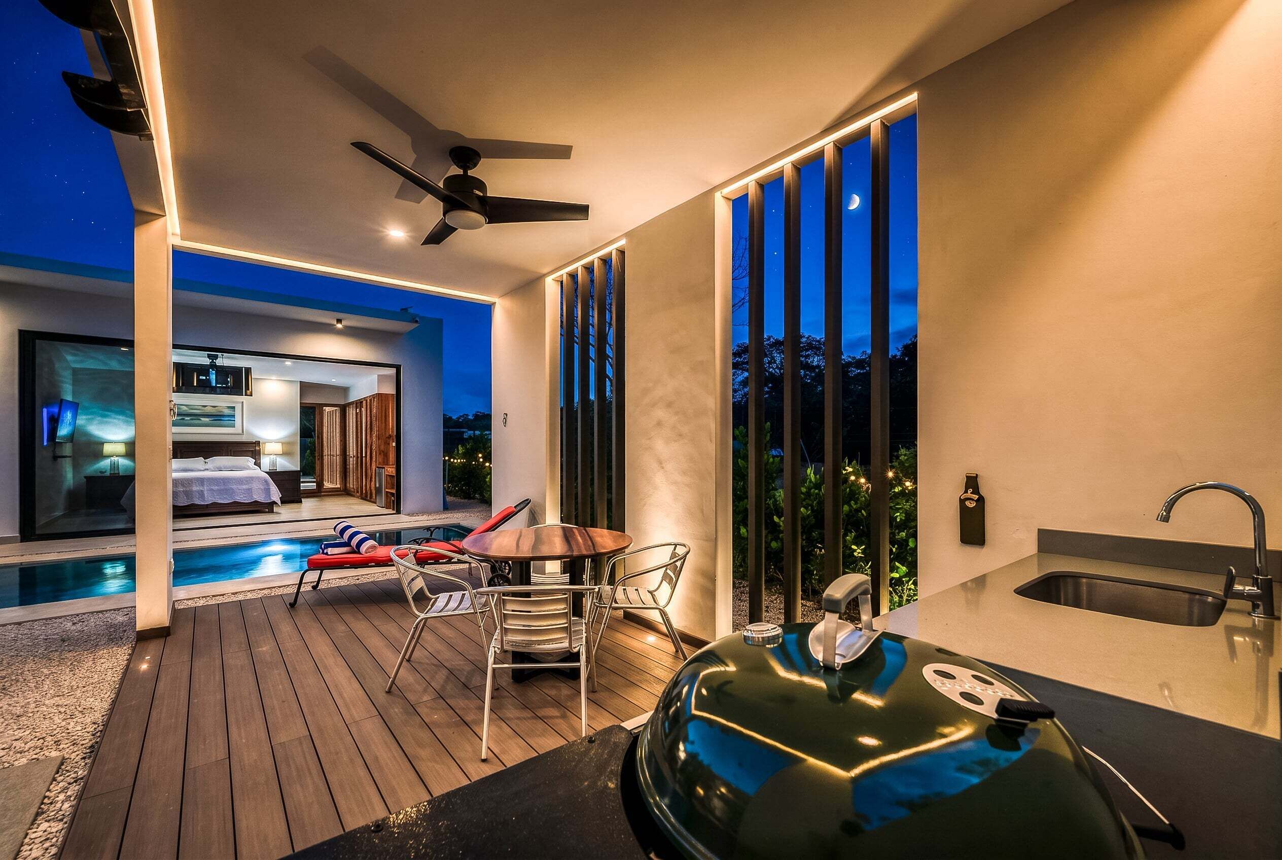 Ein moderner Außenbereich mit Pool, Esstisch mit Stühlen und Grill.