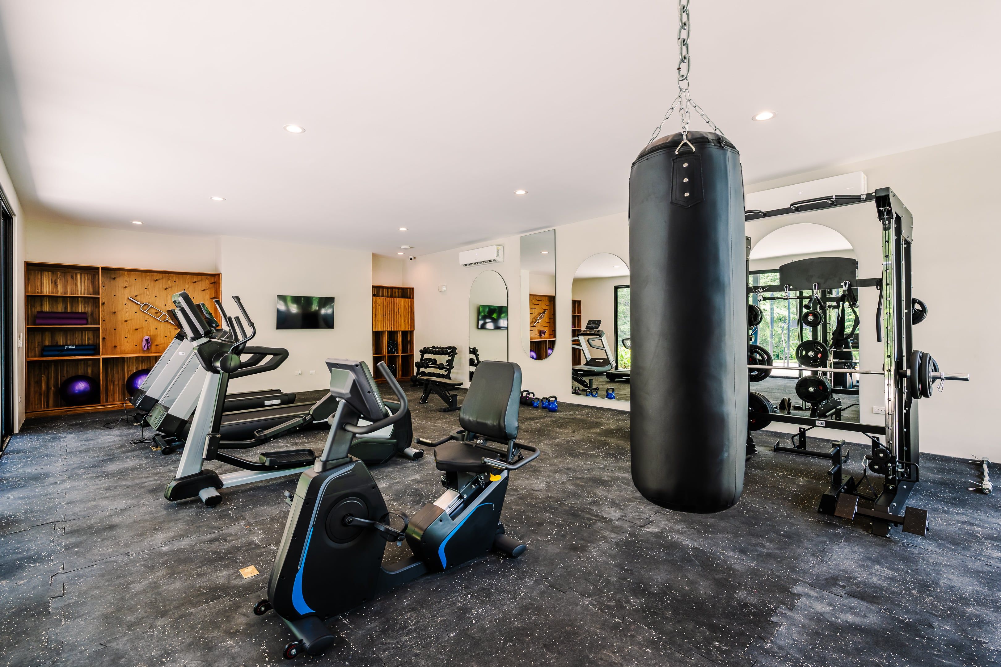 A gym with cardio machines, a punching bag, and weightlifting equipment.