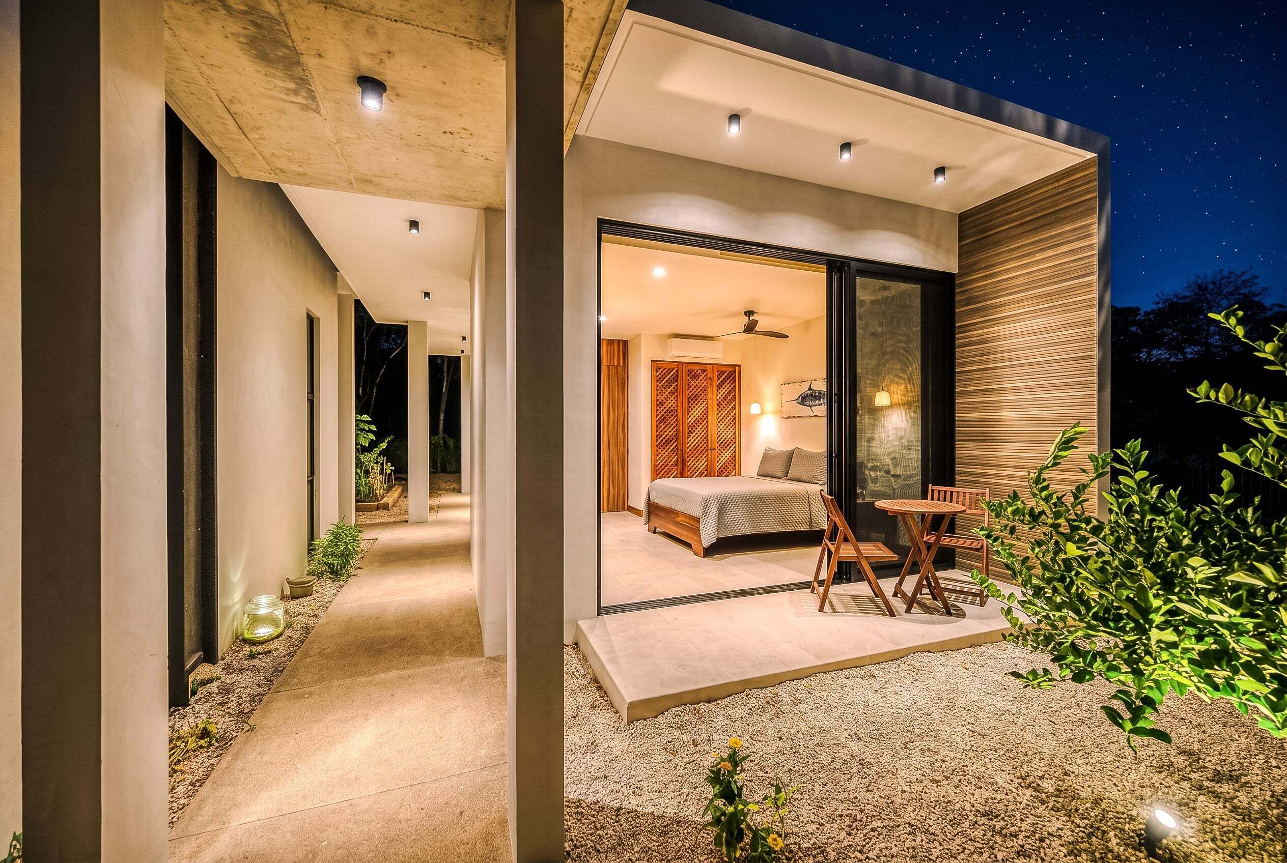 A modern house with a bedroom, a balcony, and a view of the night sky.
