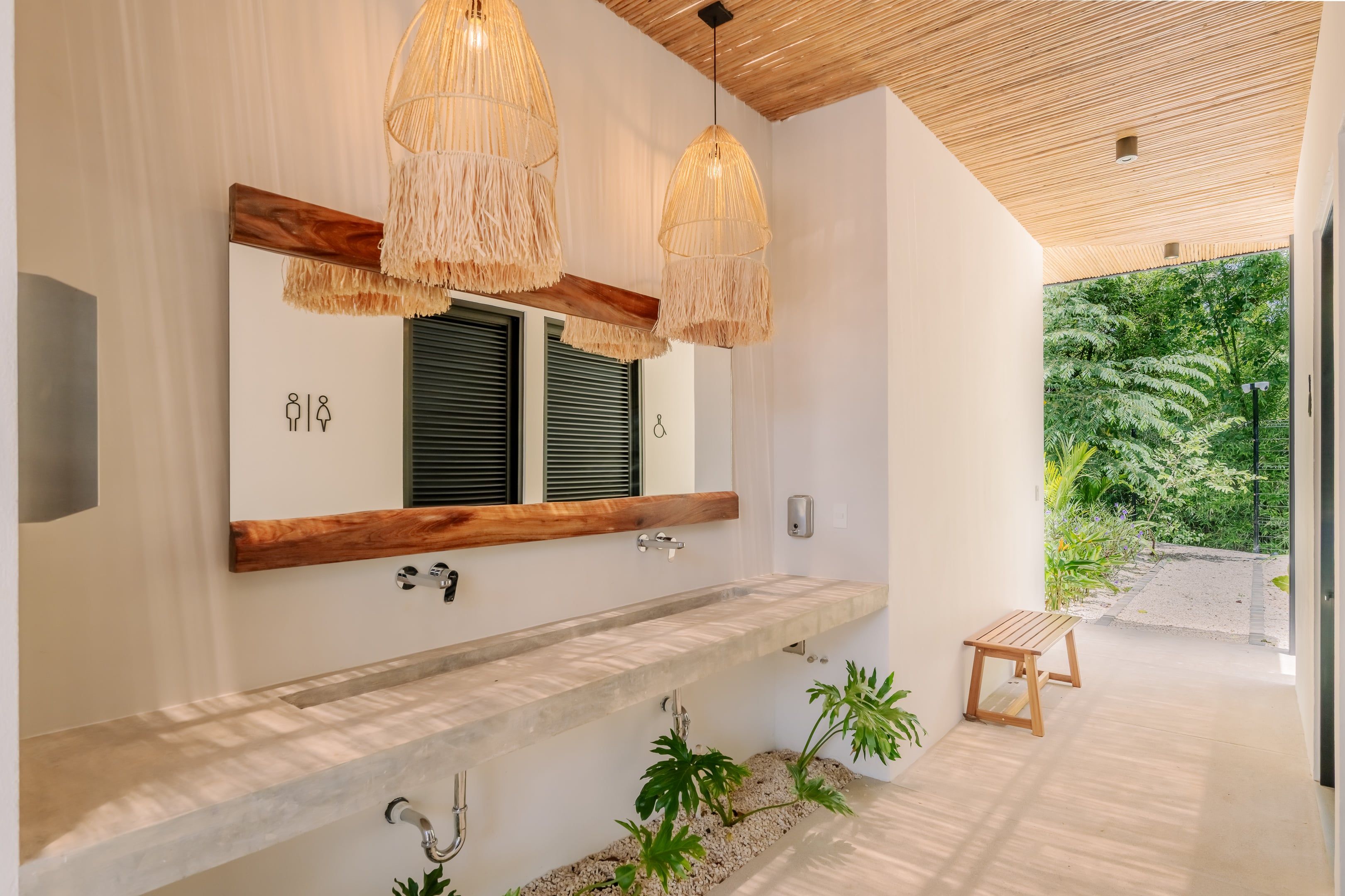 Un baño moderno con un espejo grande, vigas de madera y un banco empotrado.