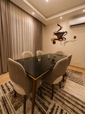 A dining area with a glass table, six chairs, and a wall decoration of a coffee cup. - Spacious 3-bedroom apartment in casa Beverly hills sodic Giza Governorate (Giza Governorate)
